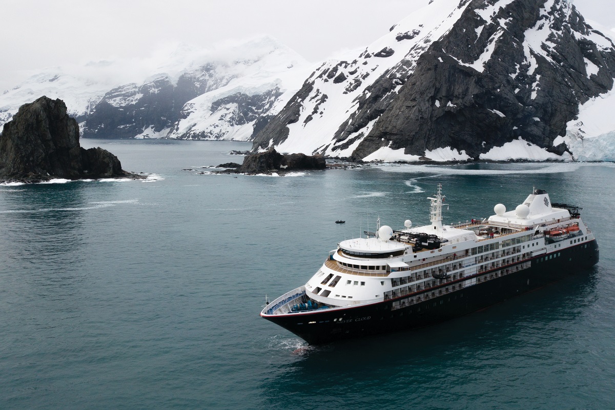 Expedition ship near dramatic Antarctic cliffs and mountains — Audley Travel bespoke voyage